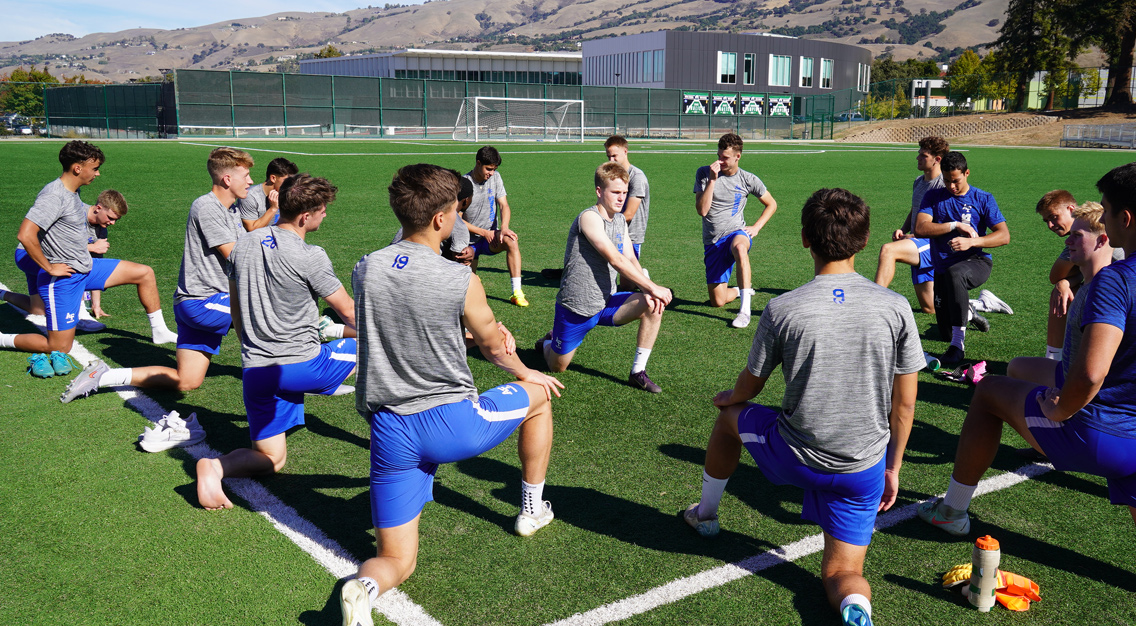 group of players stretching in gray shirts and blue shorts